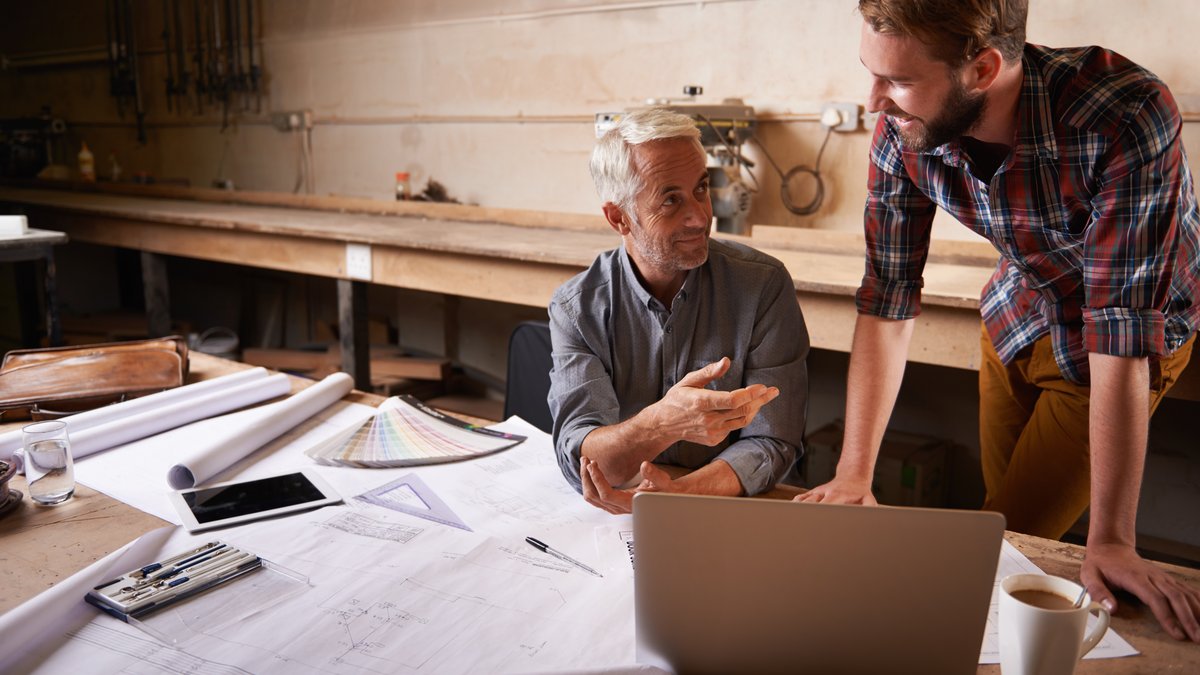 Zwei Männer mit Planungsunterlagen Das Bild zeigt einen älteren und einen jüngeren Mann beim Besprechen der Pläne.